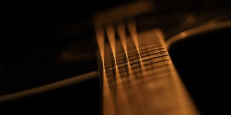 Eine schwingende Gitarrensaite in extremer Makroaufnahme auf naturbelassenem Holz zur Darstellung der Resonanz-Wellenlänge.